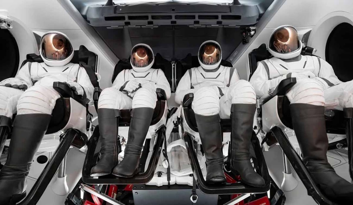 Astronautas sentados en el módulo espacial utilizando trajes espaciales.